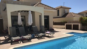 A swimming pool with lounge chairs and umbrellas, a tiled roof, and a small child’s ride nearby. - Beautiful detached villa with private pool. Sea & mountain views (Pissouri)