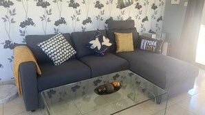 A living room with a dark sofa, patterned cushions, a glass coffee table, and floral wallpaper. - Beautiful detached villa with private pool. Sea & mountain views (Pissouri)