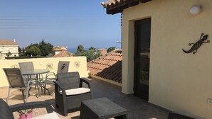A rooftop patio with wicker furniture, a table, and chairs. - Beautiful detached villa with private pool. Sea & mountain views (Pissouri)
