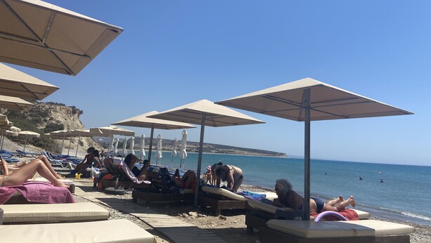 A beach with sun loungers and umbrellas, a rocky cliff in the background, and the sea. - Beautiful detached villa with private pool. Sea & mountain views (Pissouri)