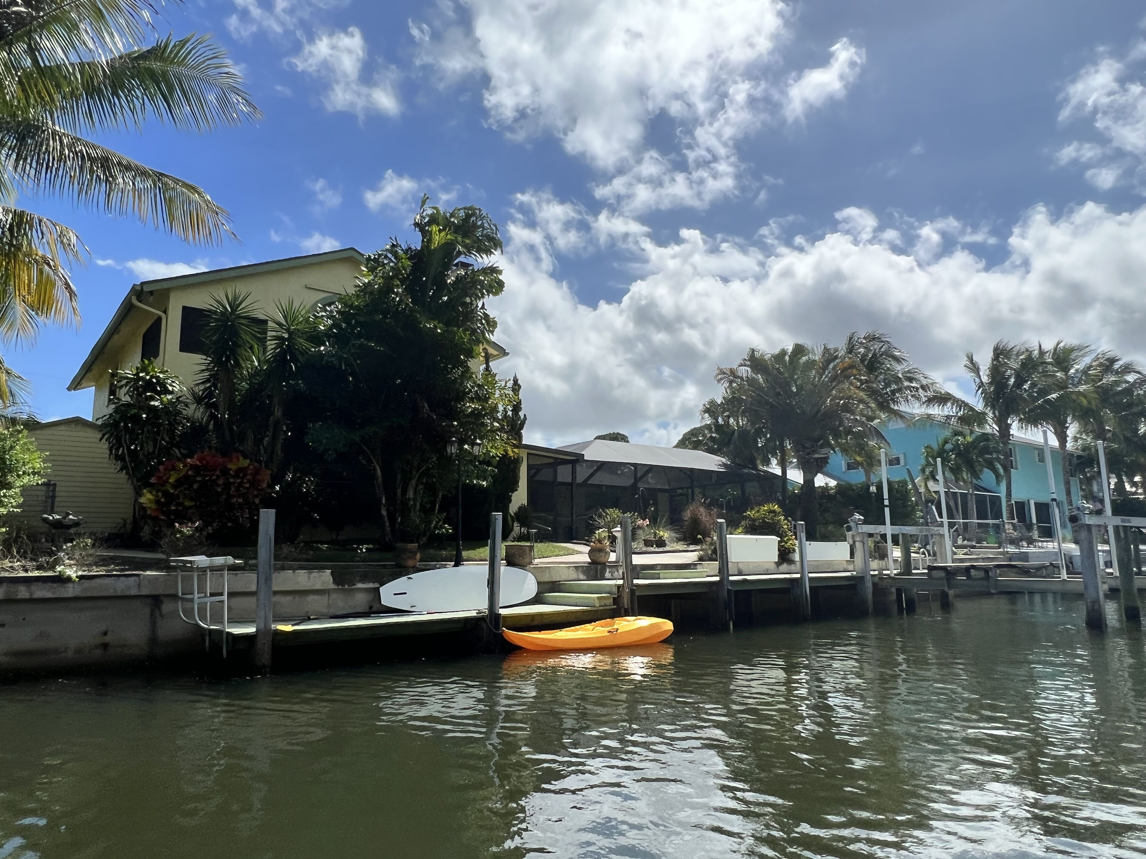 Ein Anwesen am Wasser mit Anlegesteg, einem Kajak und einem Haus, umgeben von Palmen.