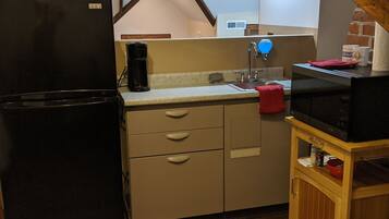 Een kleine keuken met een koelkast, wastafel en magnetron.