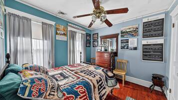 A bedroom with a bed, a ceiling fan, a dresser, and a chair.