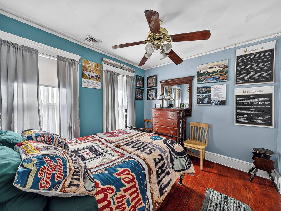 A bedroom with a bed, a ceiling fan, a dresser, and a chair.