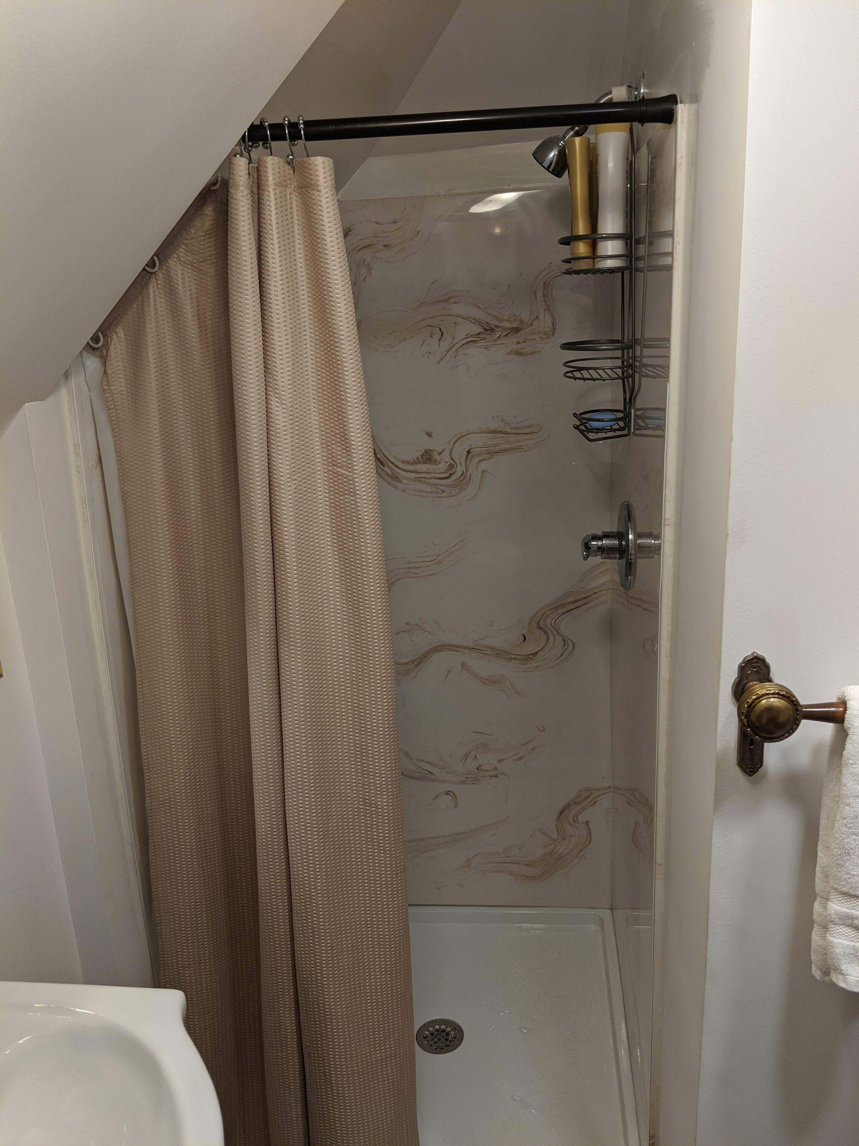 A bathroom with a shower, a towel rack, and a toilet.