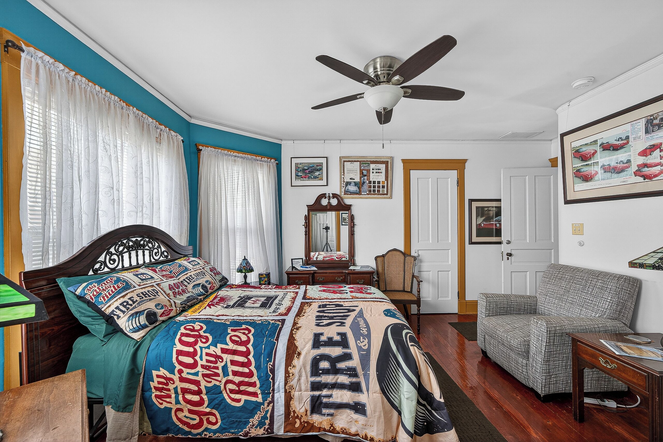 A bedroom with a bed, a ceiling fan, a chair, and a dresser.