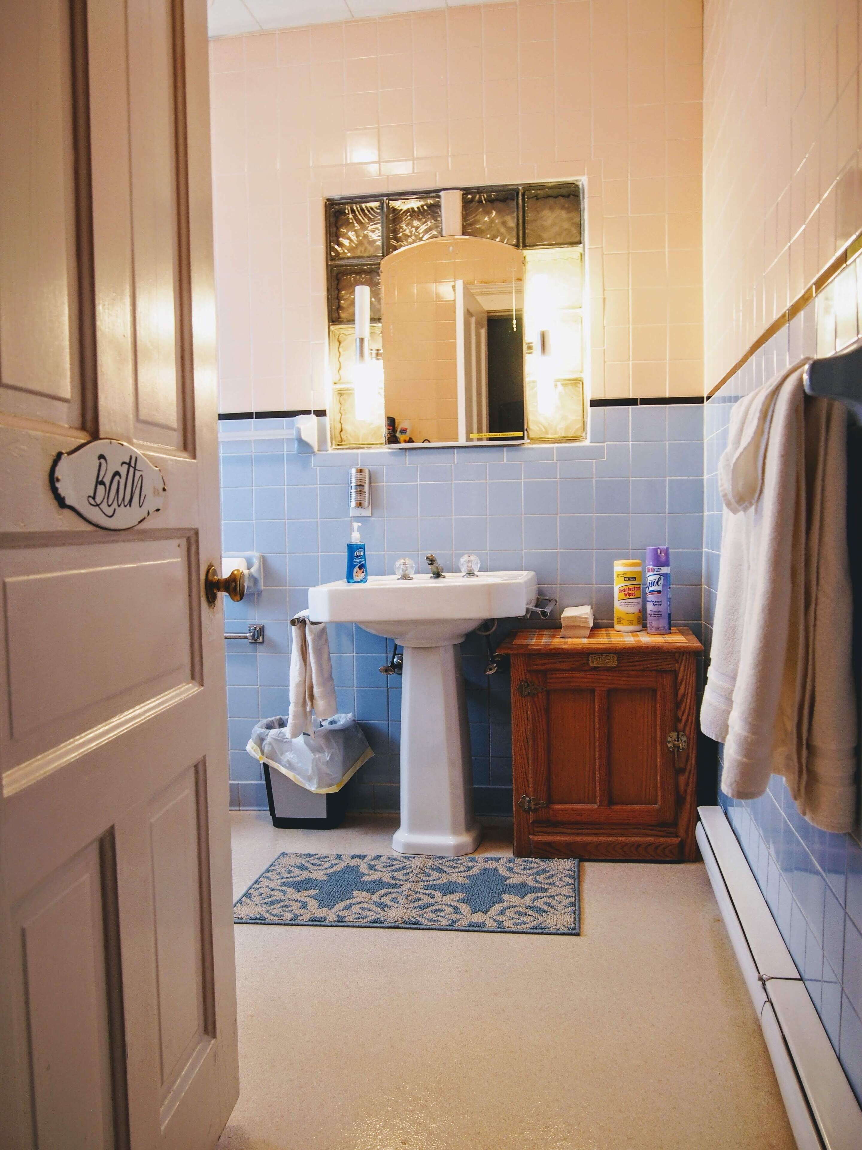 Un baño con lavamanos, espejo, toallero y una puerta con la leyenda 'Baño'.