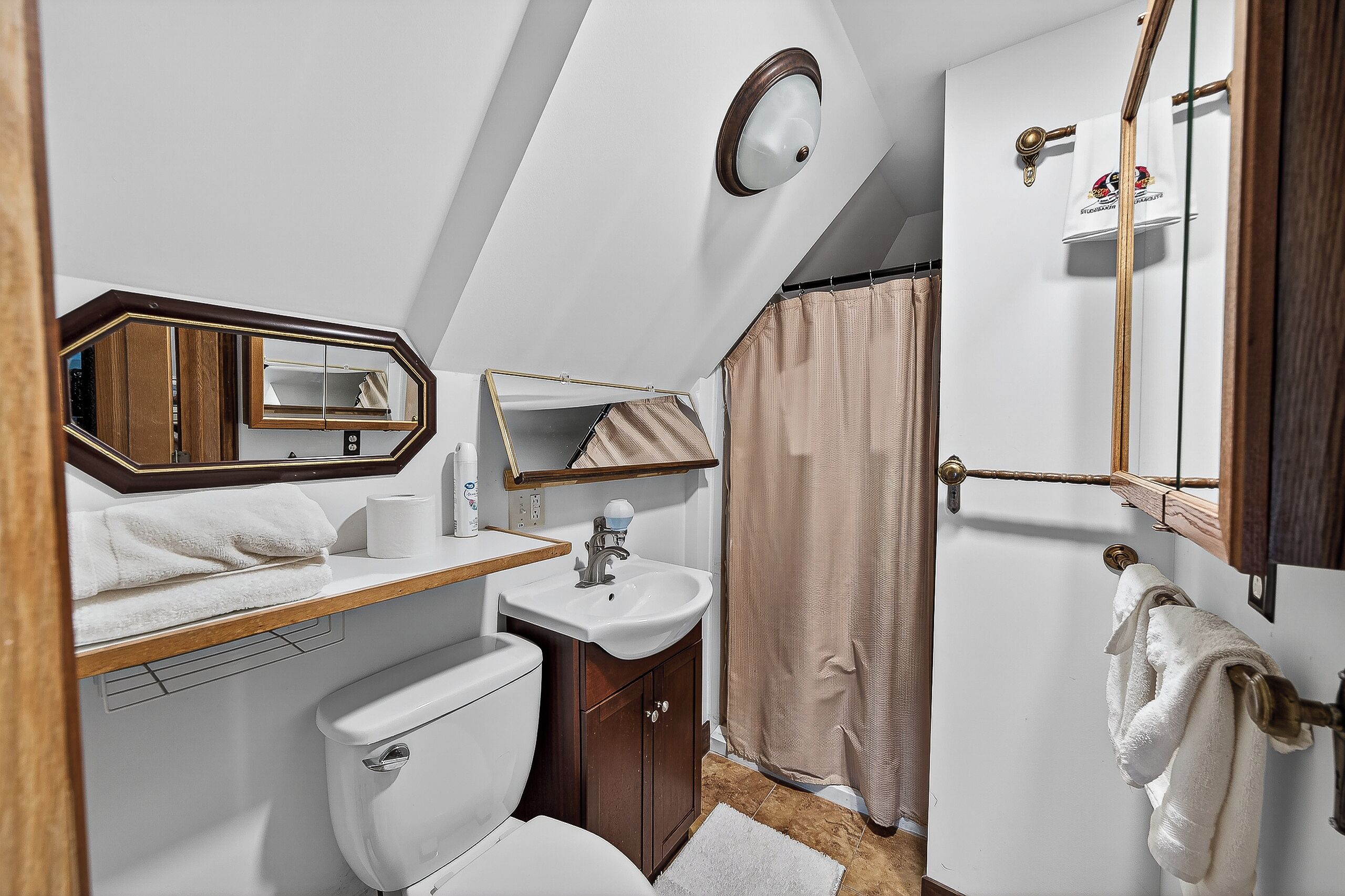 Une petite salle de bain comprenant des toilettes, un lavabo, un miroir et un rideau de douche.