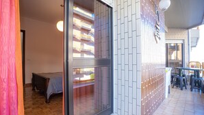 Una stanza con una porta finestra, un letto, un tavolino e una sedia.