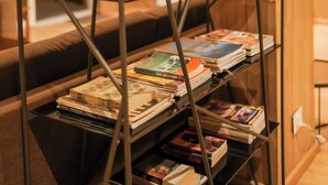 A metal bookcase with multiple shelves filled with books and magazines.