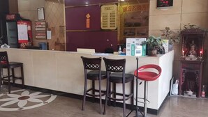 A reception area with a counter, three bar stools, a clock, and a small shrine. - kang tai gong yi (Dongguan)