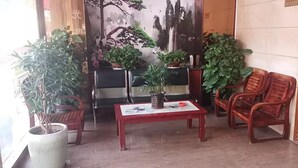 A lobby with a red coffee table, wooden chairs, and potted plants. - kang tai gong yi (Dongguan)