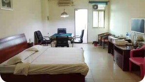 A hotel room with a bed, desk, chairs, a television, and a window. - kang tai gong yi (Dongguan)