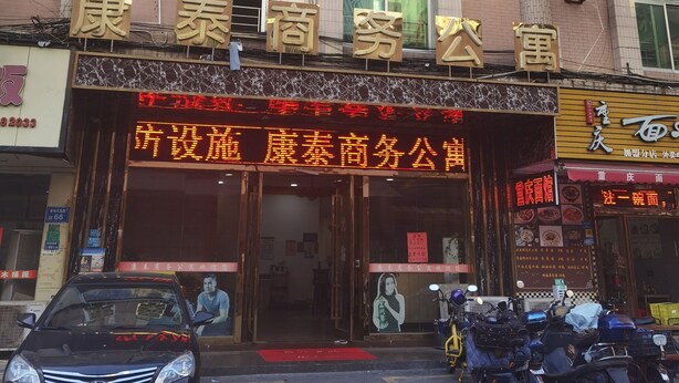 A building with multiple air conditioning units on the facade, a prominent sign with Chinese characters, and a red awning over the entrance. - kang tai gong yi (Dongguan)