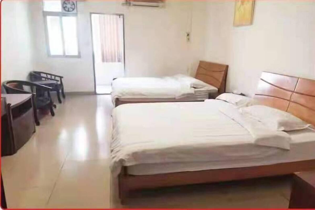 A room with two single beds, a desk, and a chair.