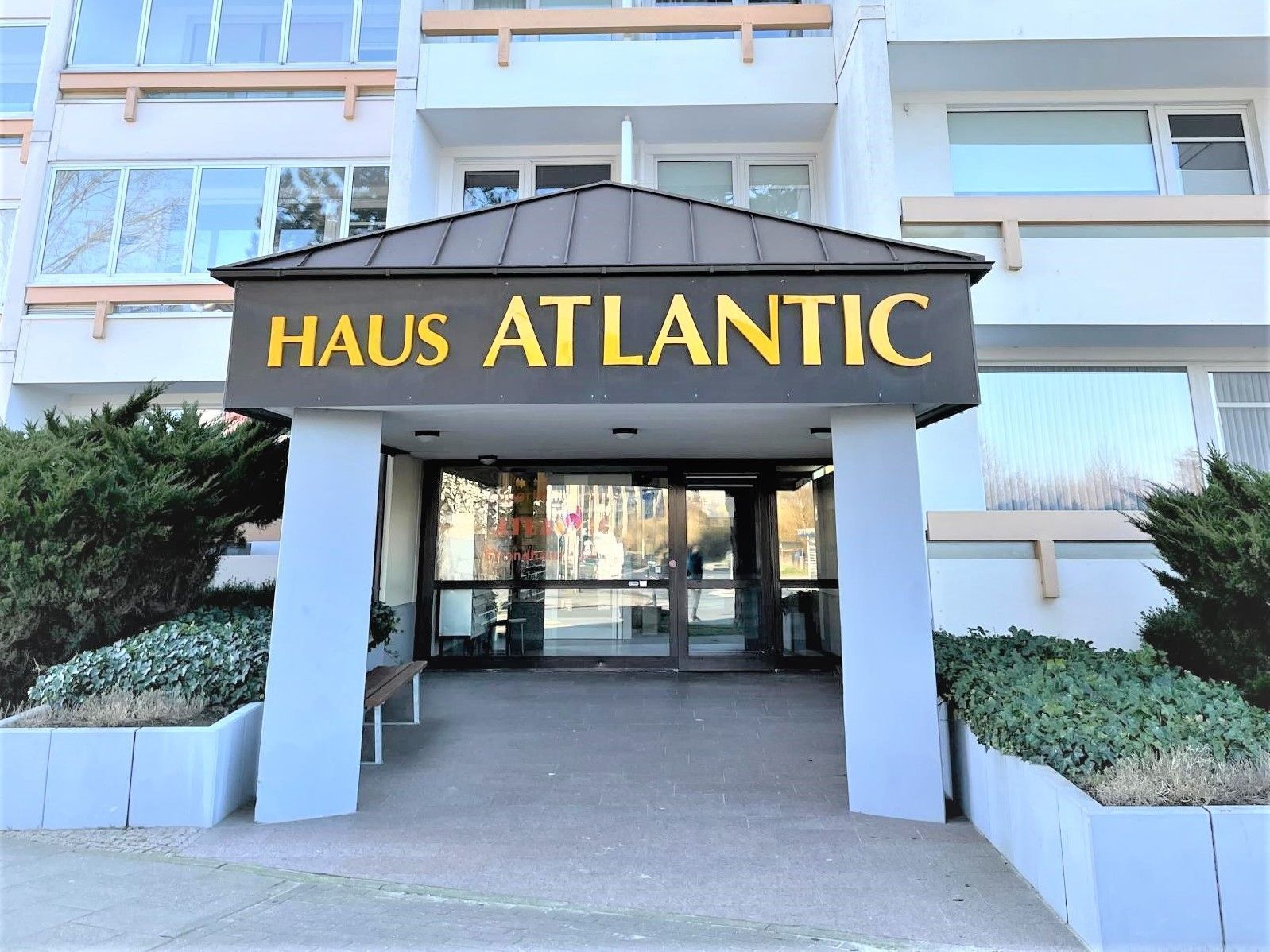 The entrance to Haus Atlantic, featuring a modern design with a prominent sign and a covered walkway.