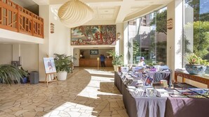 Un hall d’entrée avec un comptoir de réception, une grande fresque murale et une table avec des magazines.