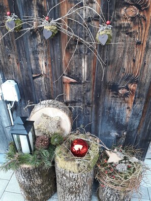Un'ambientazione rustica all'aperto, con uno sfondo in legno, un lanternino e una composizione decorativa su tronchi d'albero.
