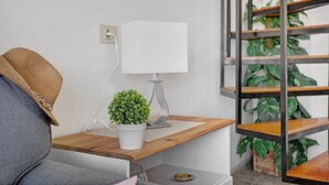 Een moderne kamer met een houten bureau, een witte lamp, een kamerplant en een trap met beplanting.