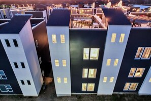 A modern apartment building with multiple units, each featuring a balcony and a small outdoor seating area.