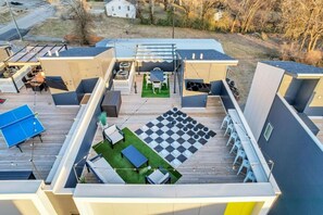 Un espacio exterior moderno con mesa de ping pong, zona de estar y piso a cuadros.