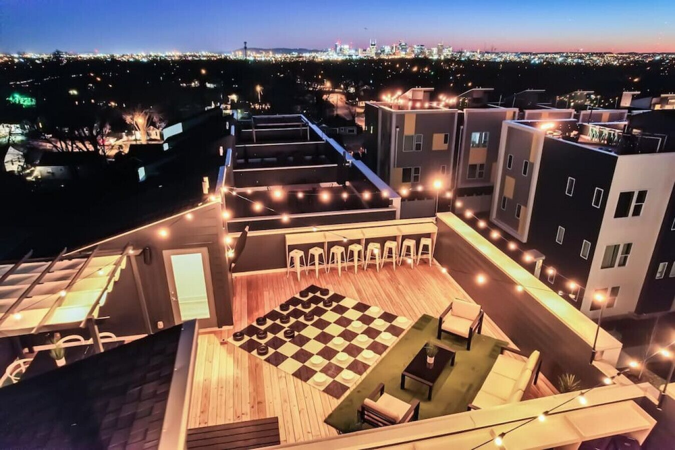 Eine Dachterrasse mit Schachbrett, Sitzgelegenheiten und Lichterketten.