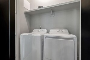 A laundry room with two stacked front-loading washing machines and a small shelf above them.