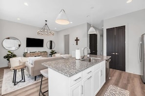 A modern kitchen with a granite countertop, white cabinetry, and a built-in island. - Tim & Faith's Rooftop - Brand New Nashville Hang Out (Nashville)