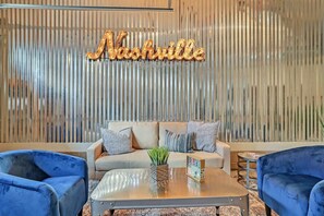 A modern interior with a sofa, two armchairs, a coffee table, and a decorative wall with a neon sign.
