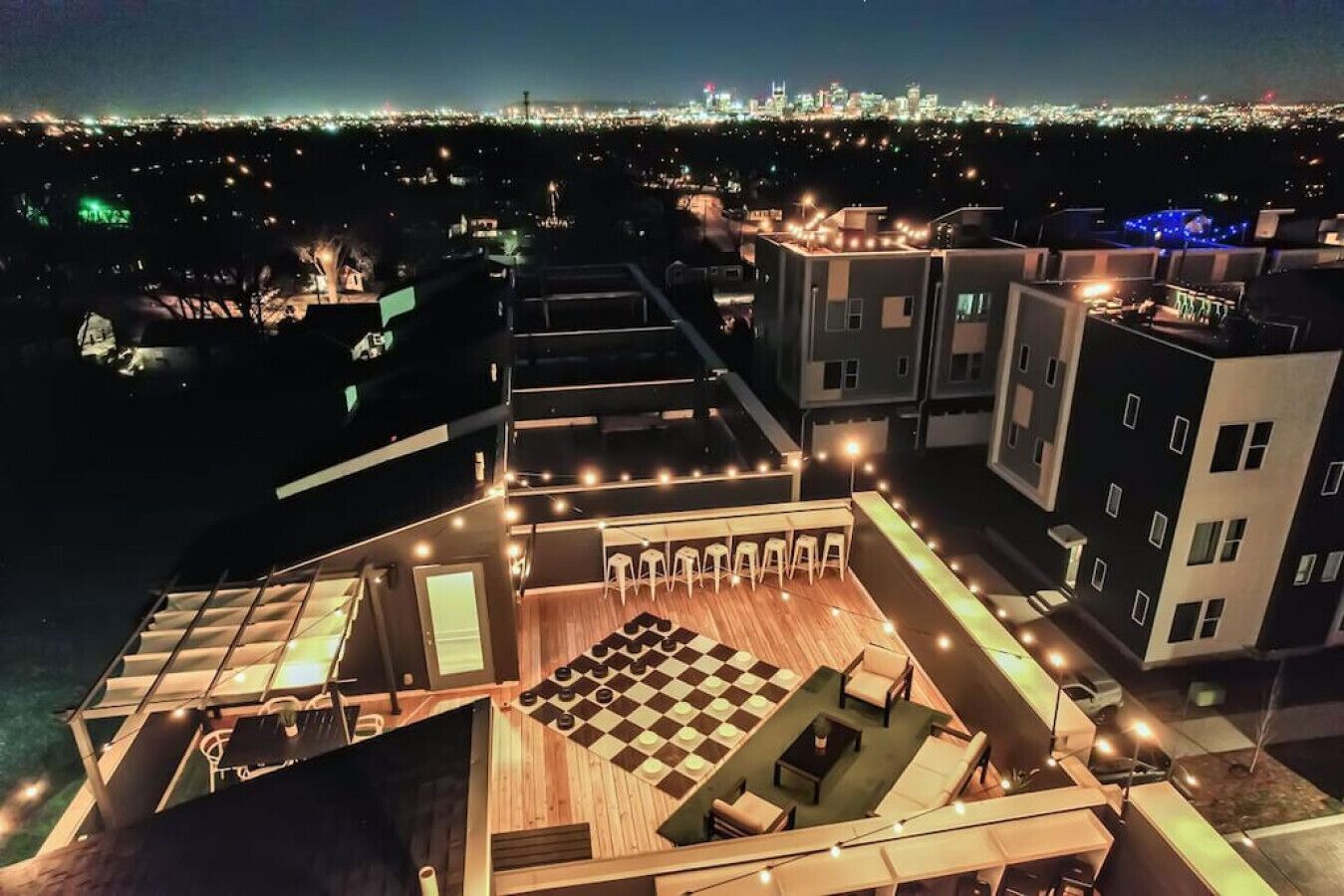 A rooftop terrace with a checkered floor, seating area, and a cityscape view.