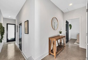 A hallway with a wooden console table, a mirror, and framed artwork on the walls. - Tim & Faith's Rooftop - Brand New Nashville Hang Out (Nashville)