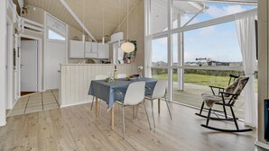 A modern kitchen with white cabinets, a dining table with chairs, and a large window offering a view of the countryside. - Cozy home in Fredericia (Fredericia)