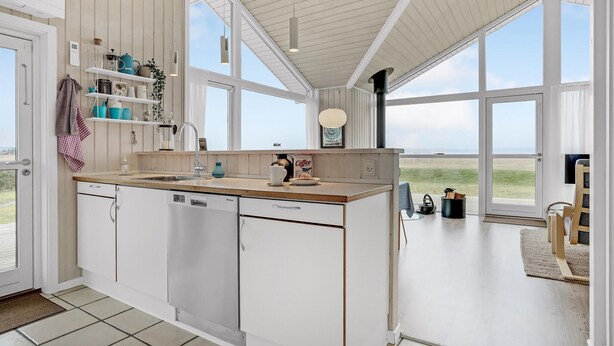 A spacious kitchen with a large island, white cabinetry, and a view of the beach. - Cozy home in Fredericia (Fredericia)
