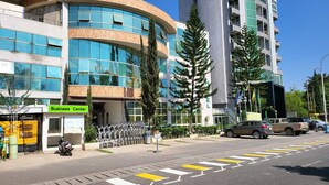 Un edificio moderno con fachada curva, un centro de negocios y un estacionamiento con marcas viales amarillas y blancas.