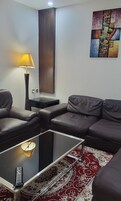 A living room with two leather sofas, a glass coffee table, a lamp, and a painting on the wall.