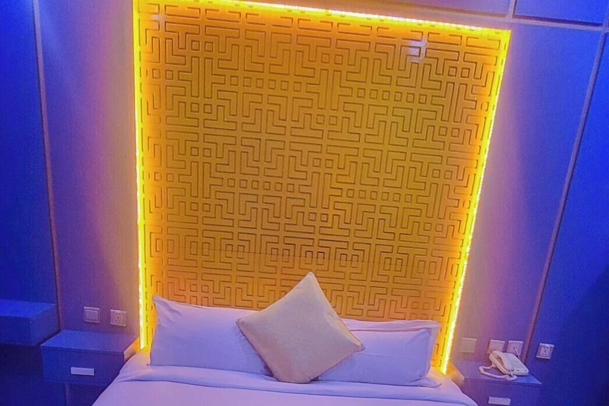 A modern hotel room with a large bed, a decorative headboard, and a neatly made bed with a decorative pillow and a folded towel.