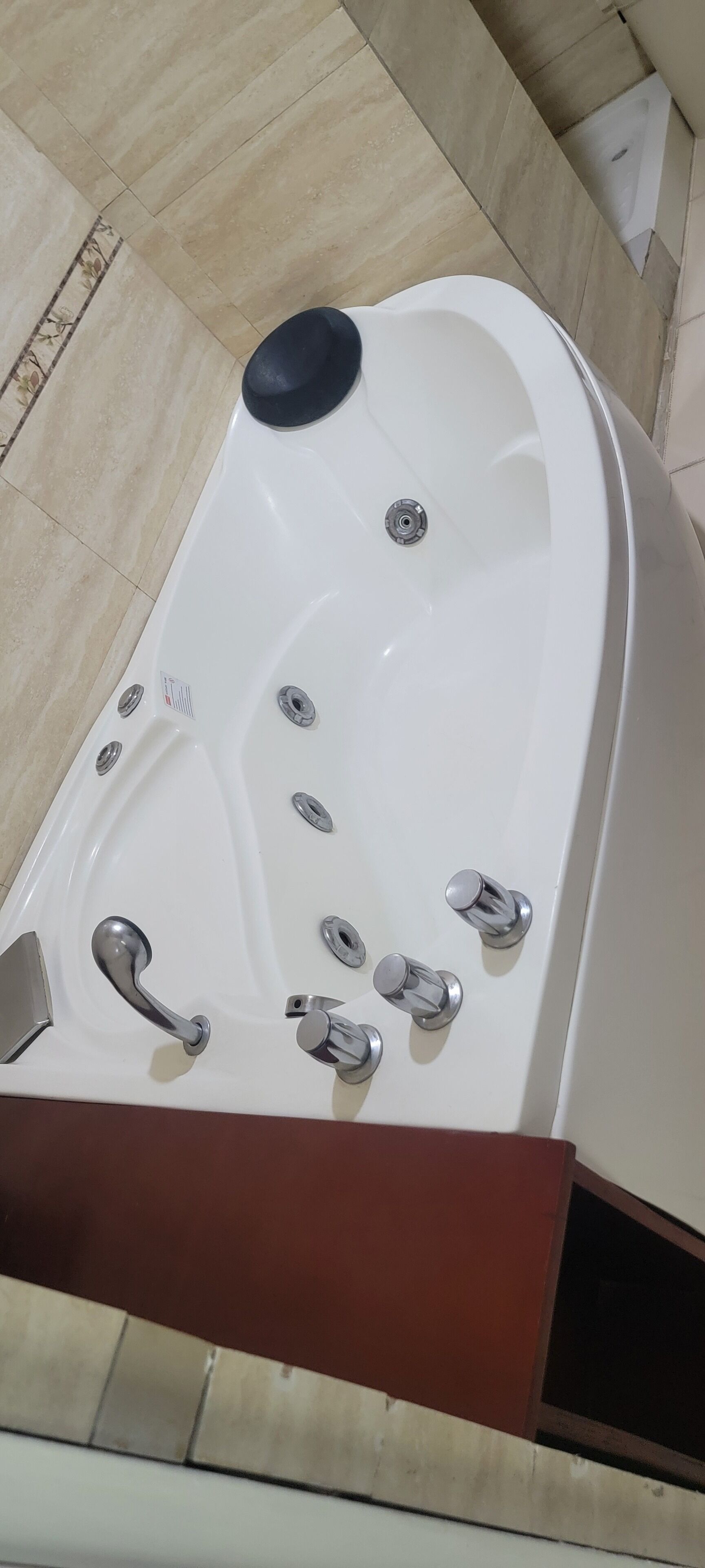 A white bathtub with multiple faucets and a black seat.