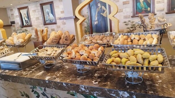 Un bufé con panes y pasteles varios.