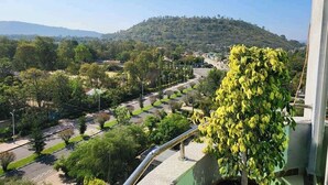 Vista desde un balcón sobre un jardín con una colina al fondo.