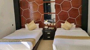 Habitación de hotel con dos camas, cabecera de madera, mesita de noche y espejo.