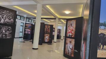 A corridor with framed photographs on display, white pillars, and a tiled floor.