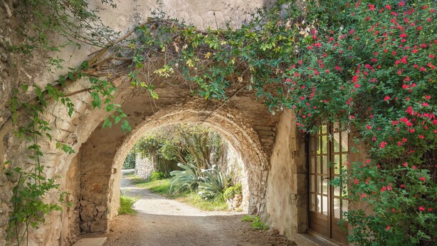 An arched stone pathway leading to a rustic building with a wooden door and a window. - Large authentic house with swimming pool and tennis court, ideal for families and friends (LABASTIDE DE VIRAC)