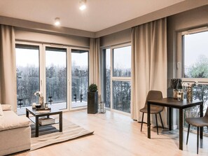 Una sala de estar moderna con ventanas amplias, un comedor y un sofá.