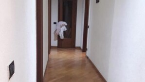 A hallway with wooden flooring, white walls, and a door at the end. - Modern and Cosy Apartment in Genoa, Italy (Genoa)