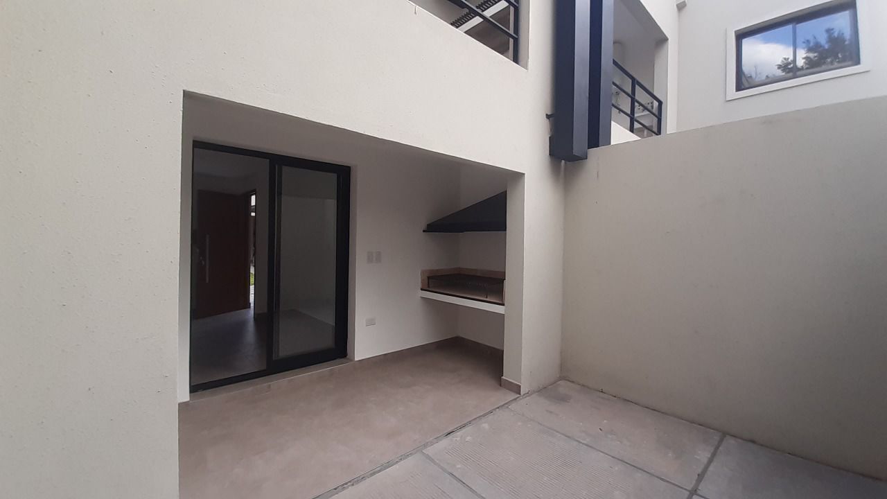 A modern, minimalist interior with a sliding glass door leading to a balcony, a small built-in shelf, and a clean, uncluttered space.