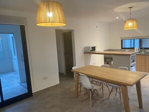 A modern kitchen with a wooden table and chairs, a microwave, and a kettle. - La Escondida Salta 4 (Salta)
