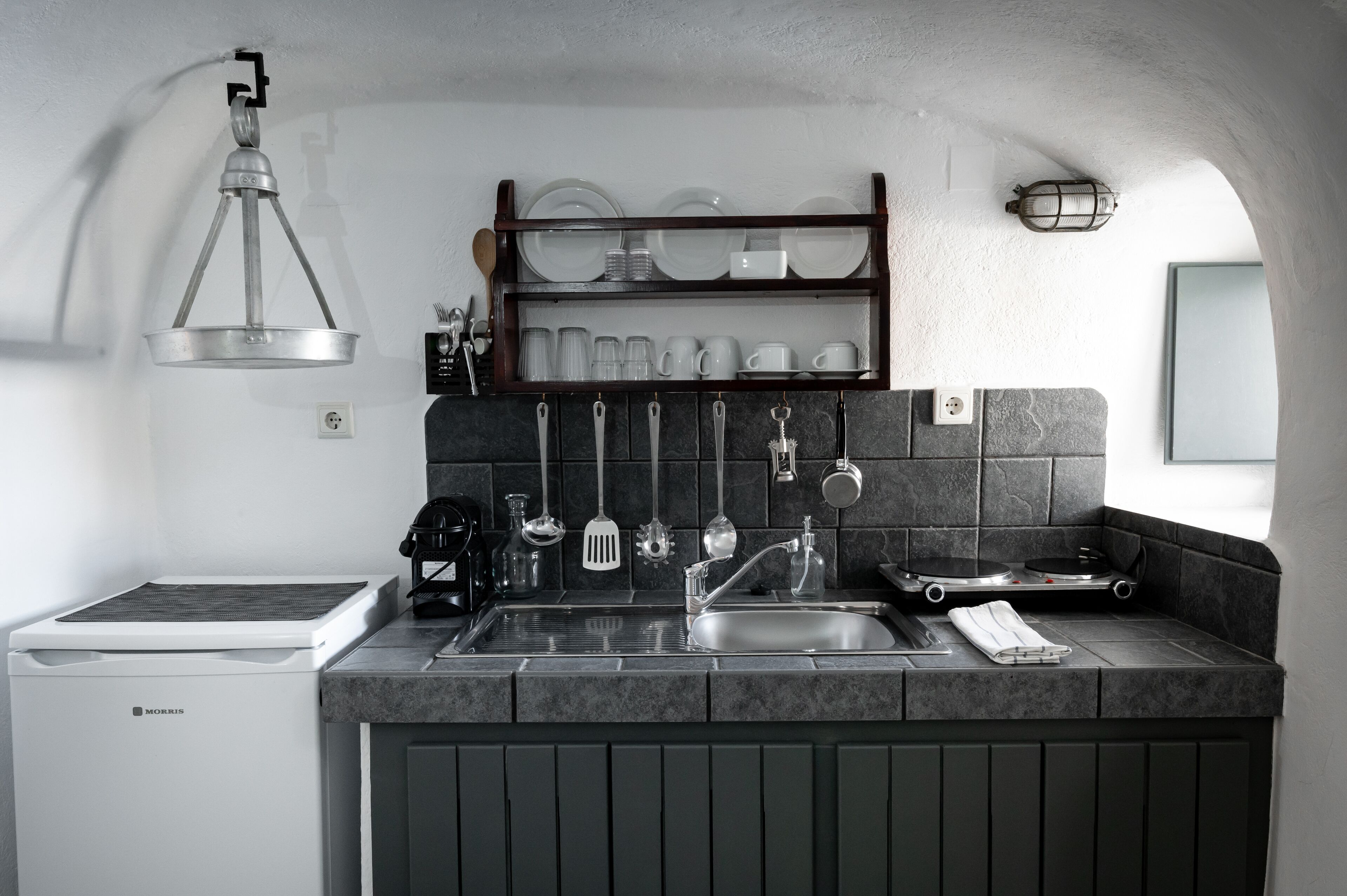 A modern kitchen with a built-in stove, a sink, and a hanging utensil rack.