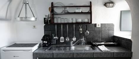 A modern kitchen with a built-in stove, a sink, and a hanging utensil rack.