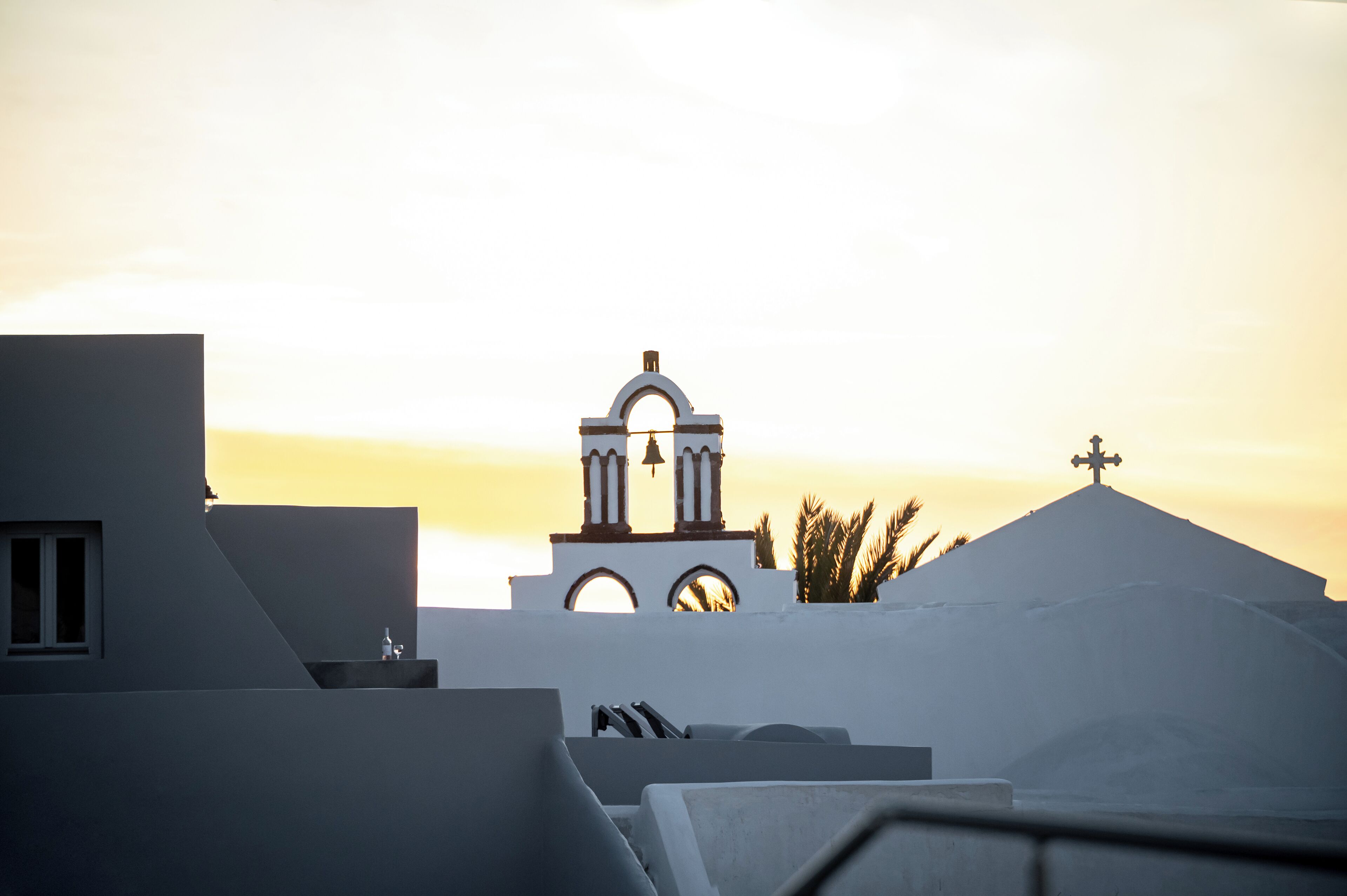 A building with a bell tower and a cross on top, overlooking a body of water.