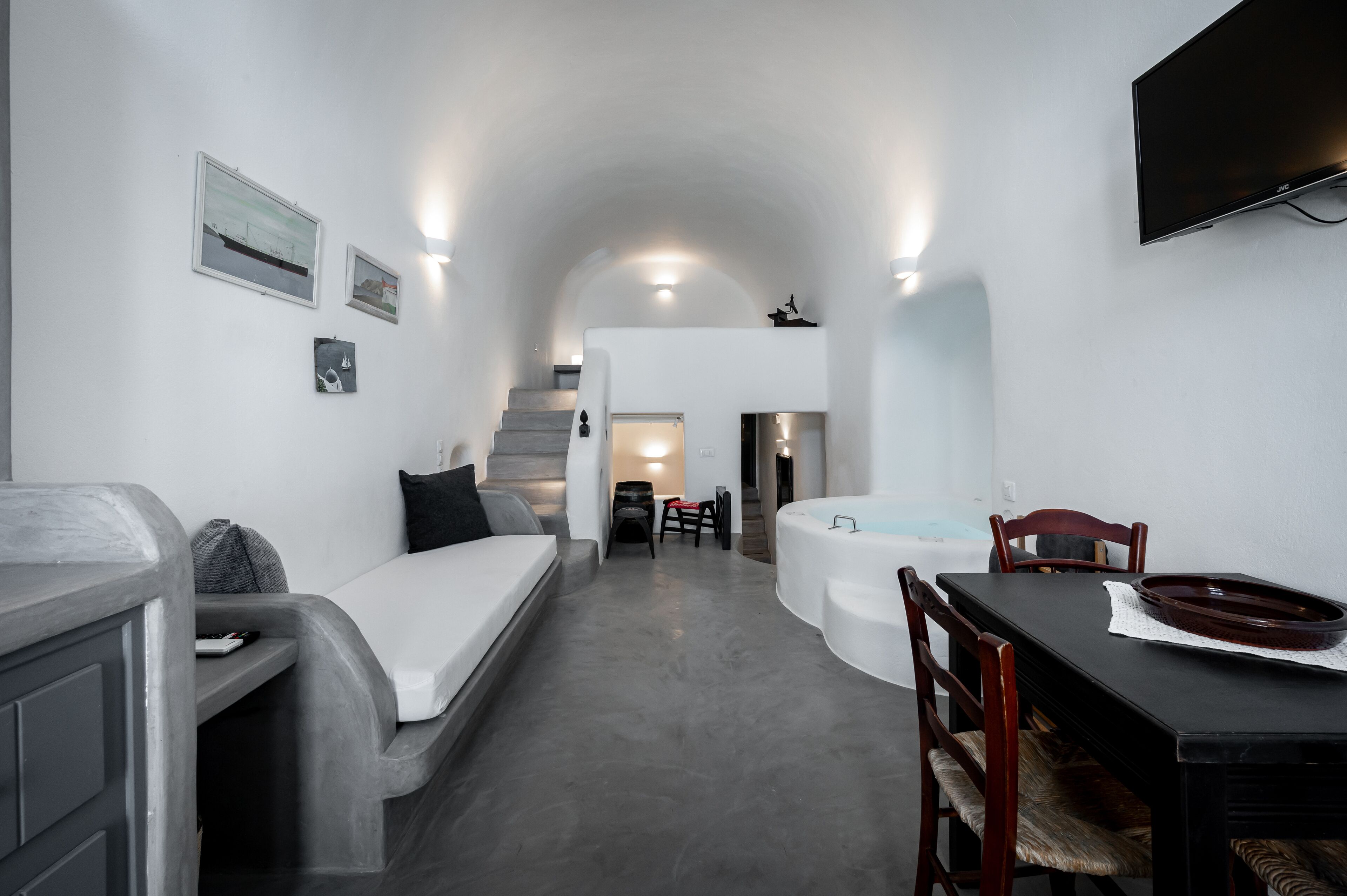 Un espace de vie compact comprenant un canapé, une table à manger avec des chaises, un petit coin cuisine et un escalier menant à un niveau supérieur.